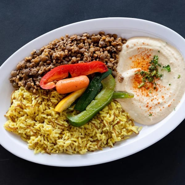 A Sultan's Restaurant Mediterranean plate with yellow rice, lentils, roasted vegetables, and hummus.