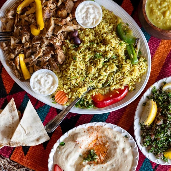A large platter of Sultan's chicken shawarma, yellow rice, hummus, tabbouleh, and pita bread.