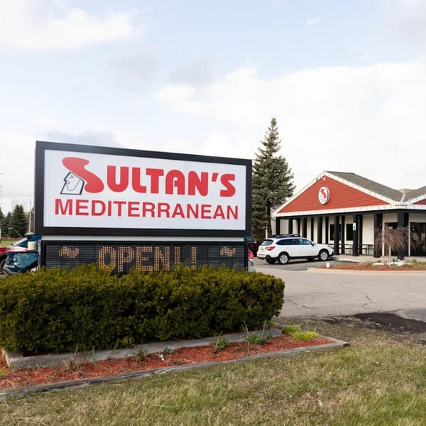 Sultan's Mediterranean restaurant exterior with a large sign displaying "OPEN!!" and parked cars.