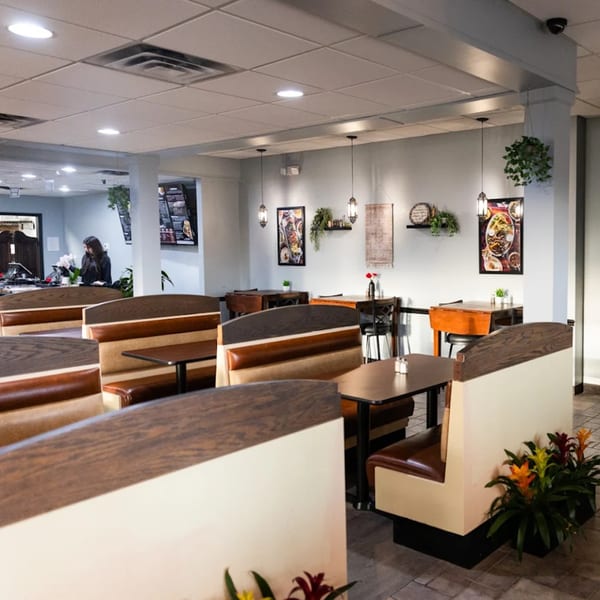 Interior of Sultan's Restaurant with empty booths, tables, and a person at the counter.