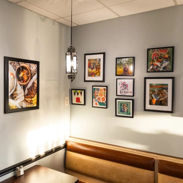 Corner booth at Sultan's Restaurant with framed art on the walls and a hanging lantern.