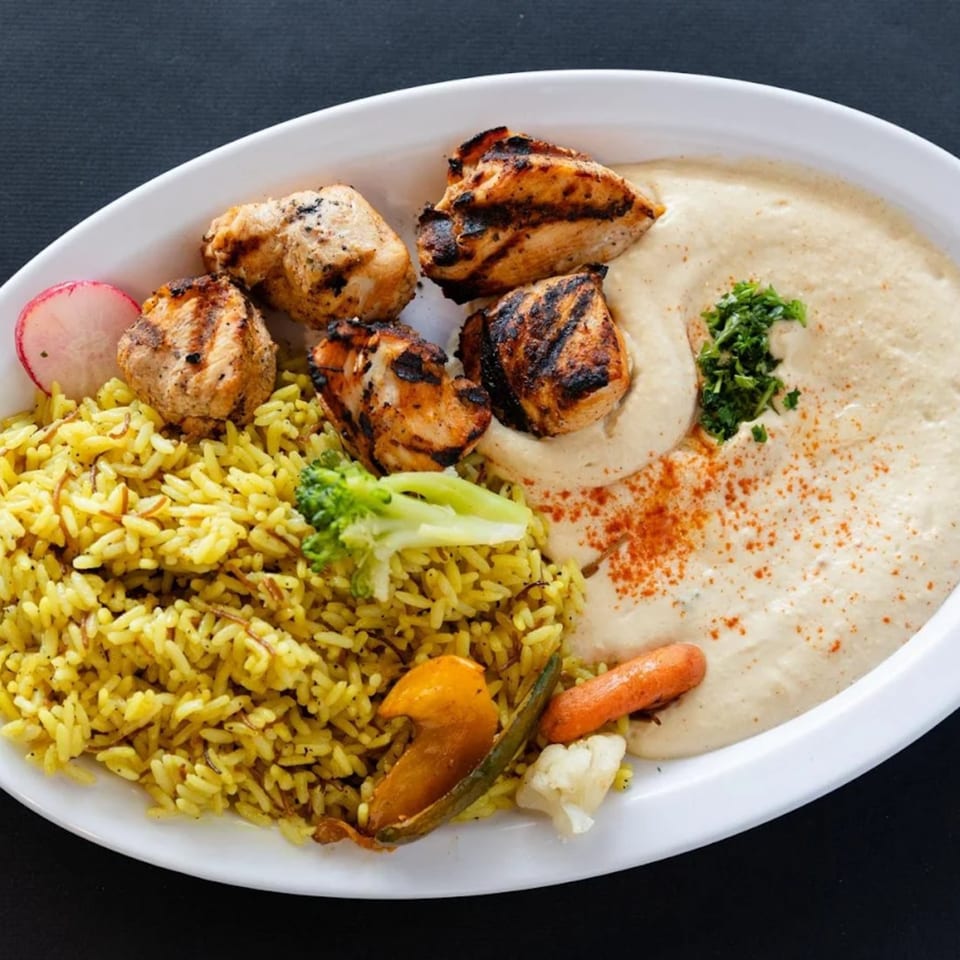 Sultan's Restaurant Mediterranean dish with grilled chicken, yellow rice, hummus, and vegetables.