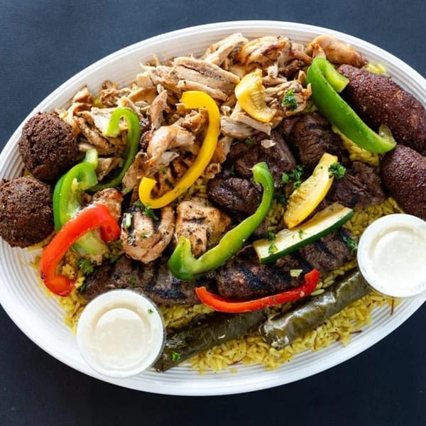 A large platter of Sultan's Mediterranean food with chicken, beef, falafel, and stuffed grape leaves.